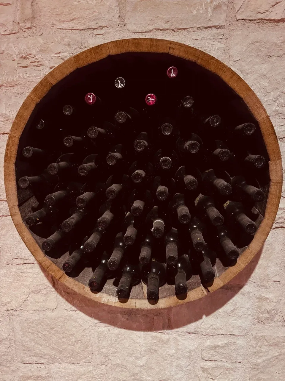 Wine bottles in a round wooden rack on a stone wall