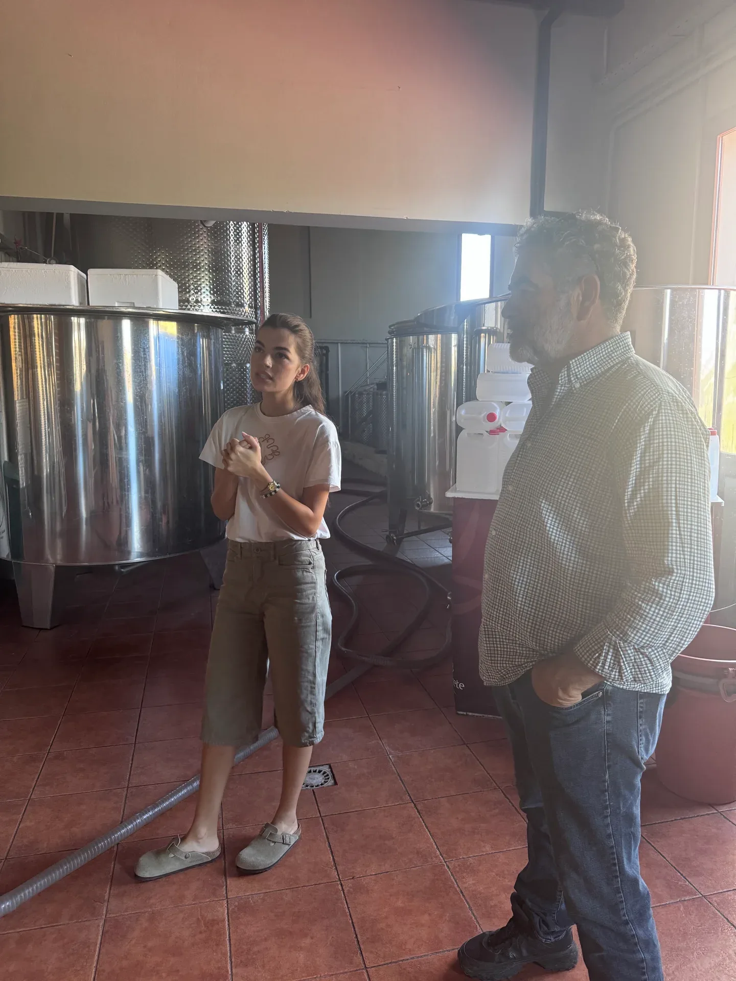 Two winery hosts talking among stainless steel tanks
