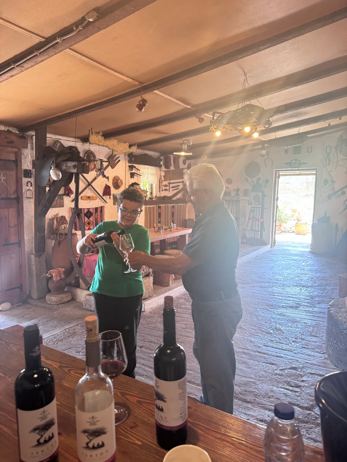 A young host pouring wine for an older family member in the tasting room