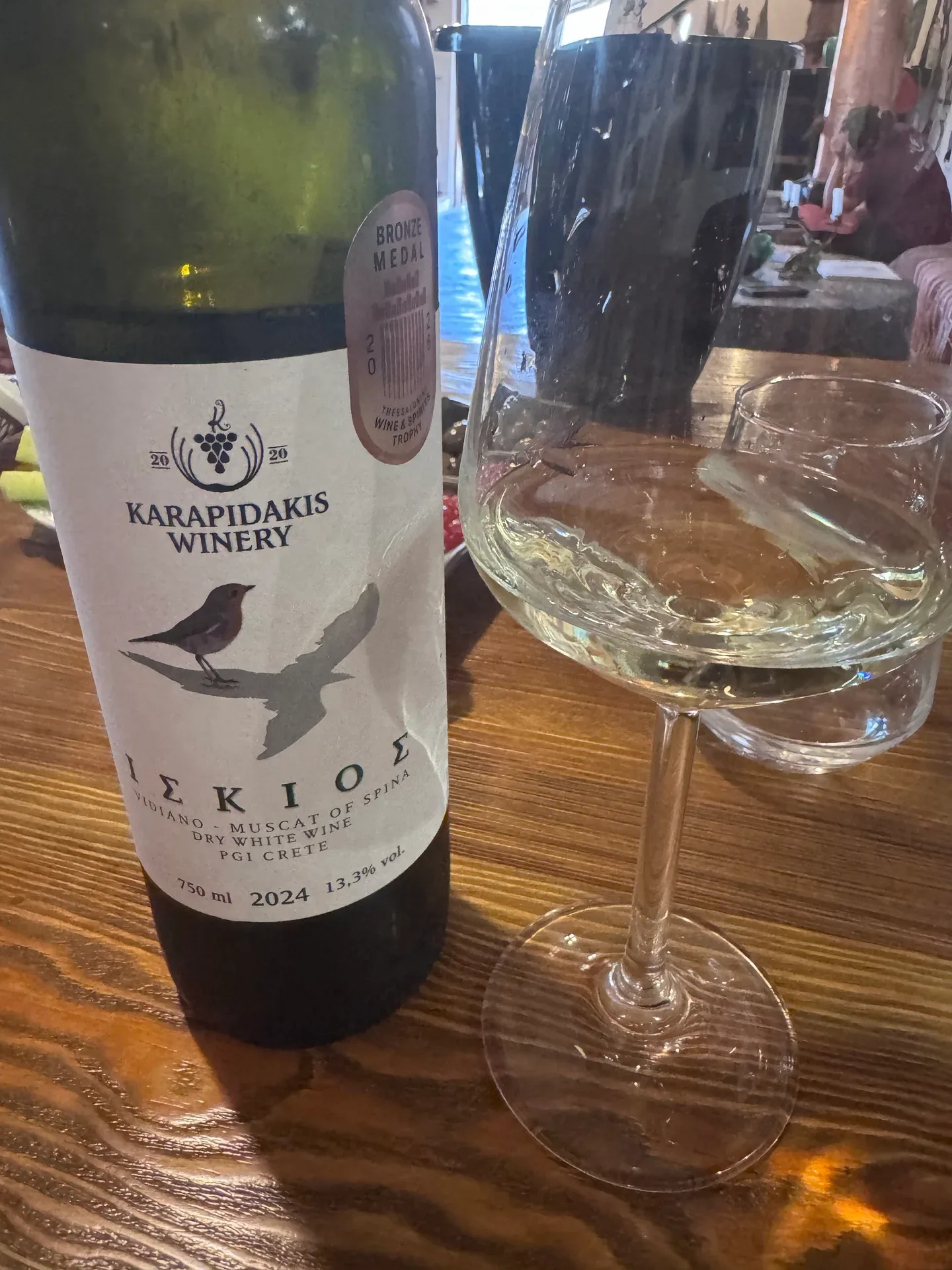 A 2024 ISKIOS Vidiano and Muscat of Spina white wine beside a wine glass
