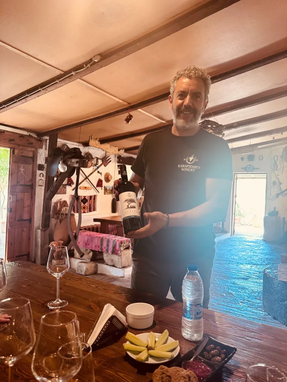A Karapidakis host presenting a bottle of ISKIOS at the tasting table