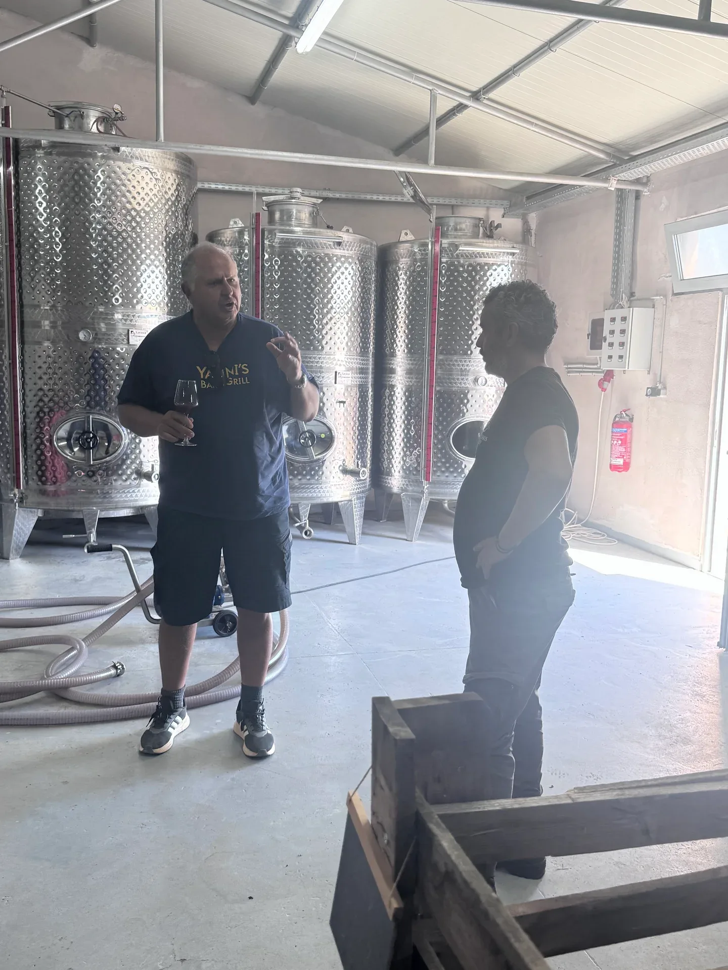 Yanni speaking with a Karapidakis host beside stainless steel tanks