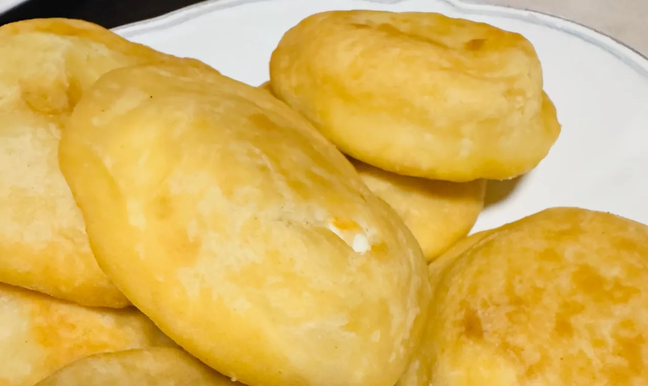 A close view of golden round pastries stacked on a white plate