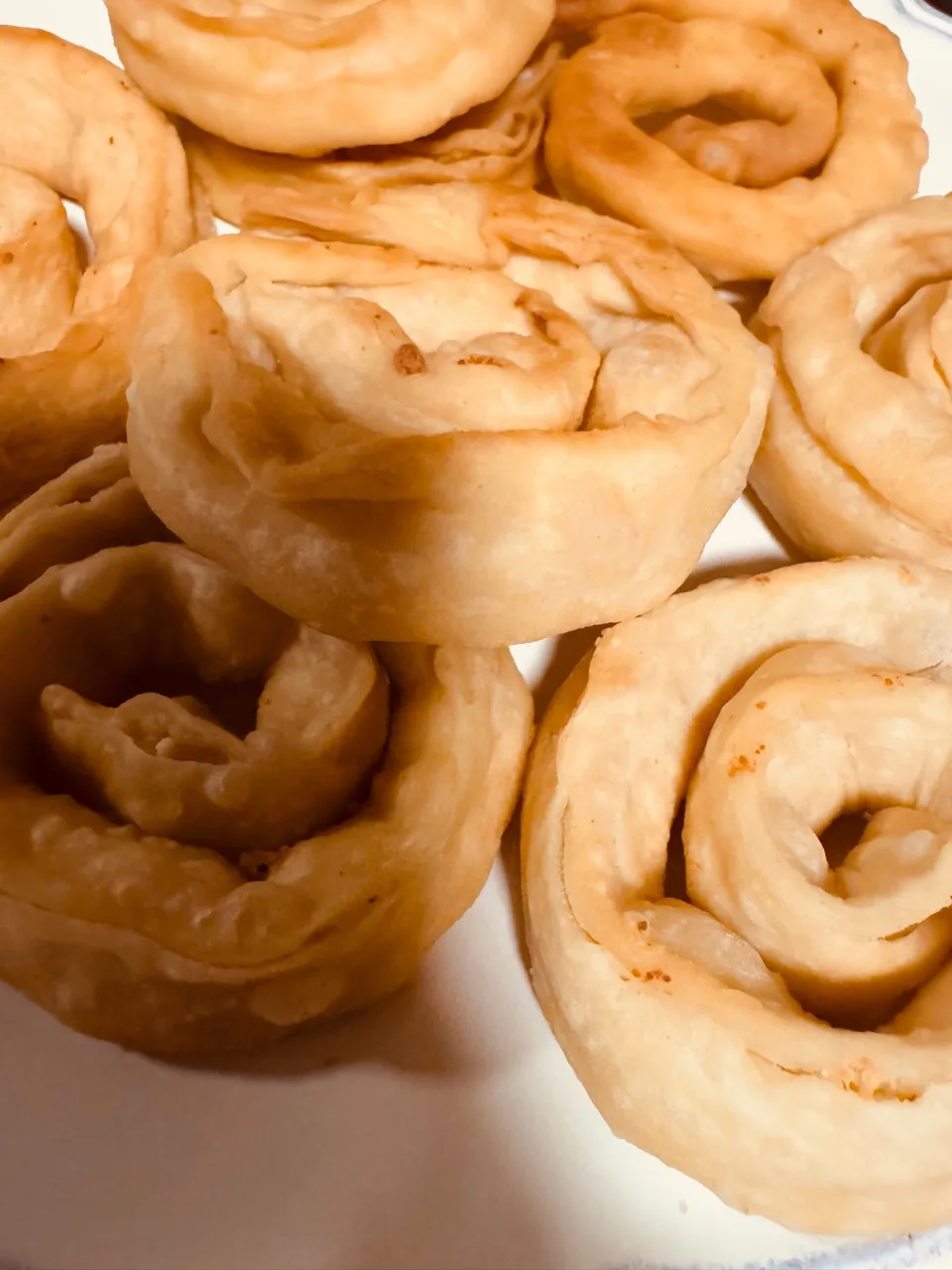 Golden spiral pastries overlapping on a white plate