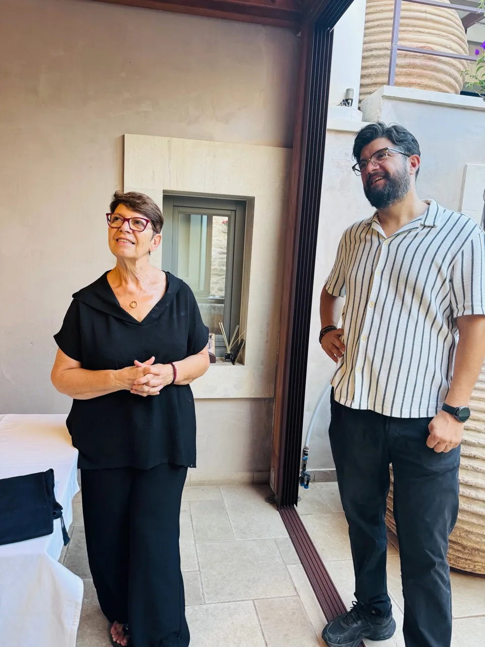 A woman in black and a man in a striped shirt standing beside the open doorway at the class