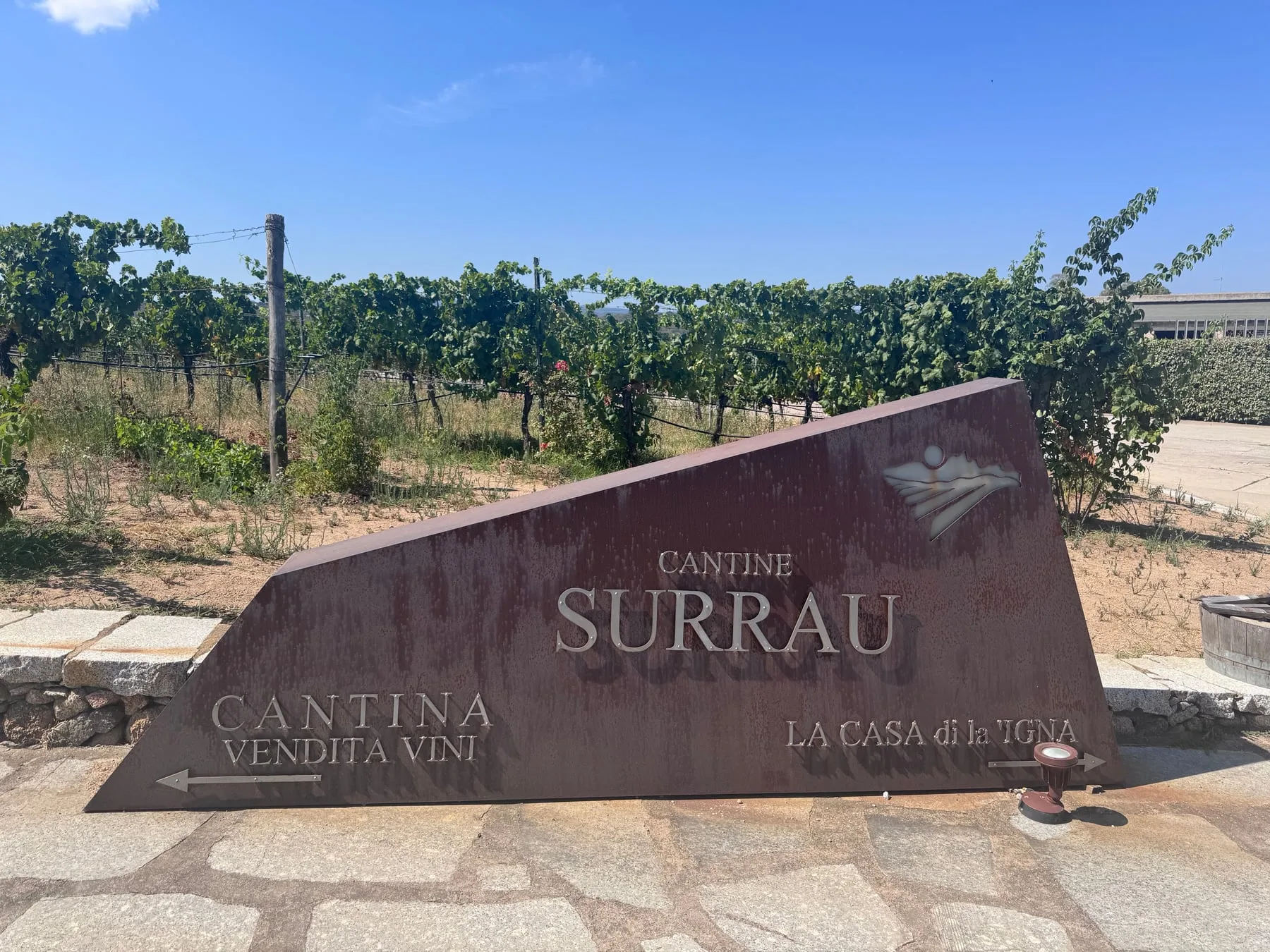 The weathered metal Cantine Surrau sign beside the vineyard