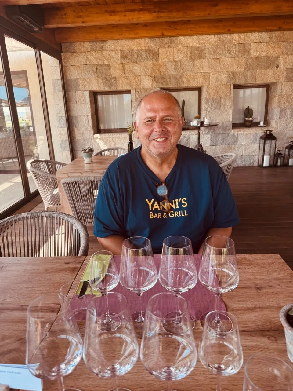 Yanni smiling behind a full flight of empty tasting glasses