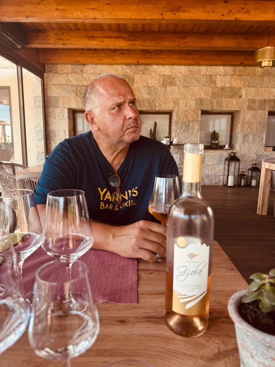 Yanni considering a glass beside a bottle of Surrau rosato