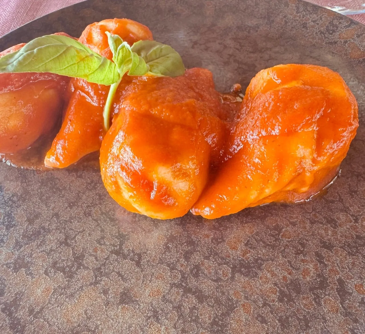 The first plated course in a bright tomato sauce with basil