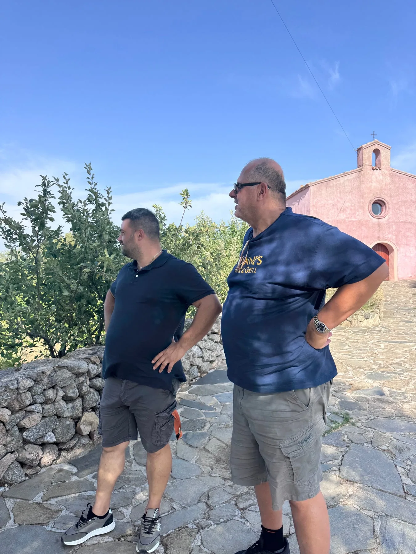 Simone Sedilesu and Yanni overlooking the vineyard beside a small pink chapel