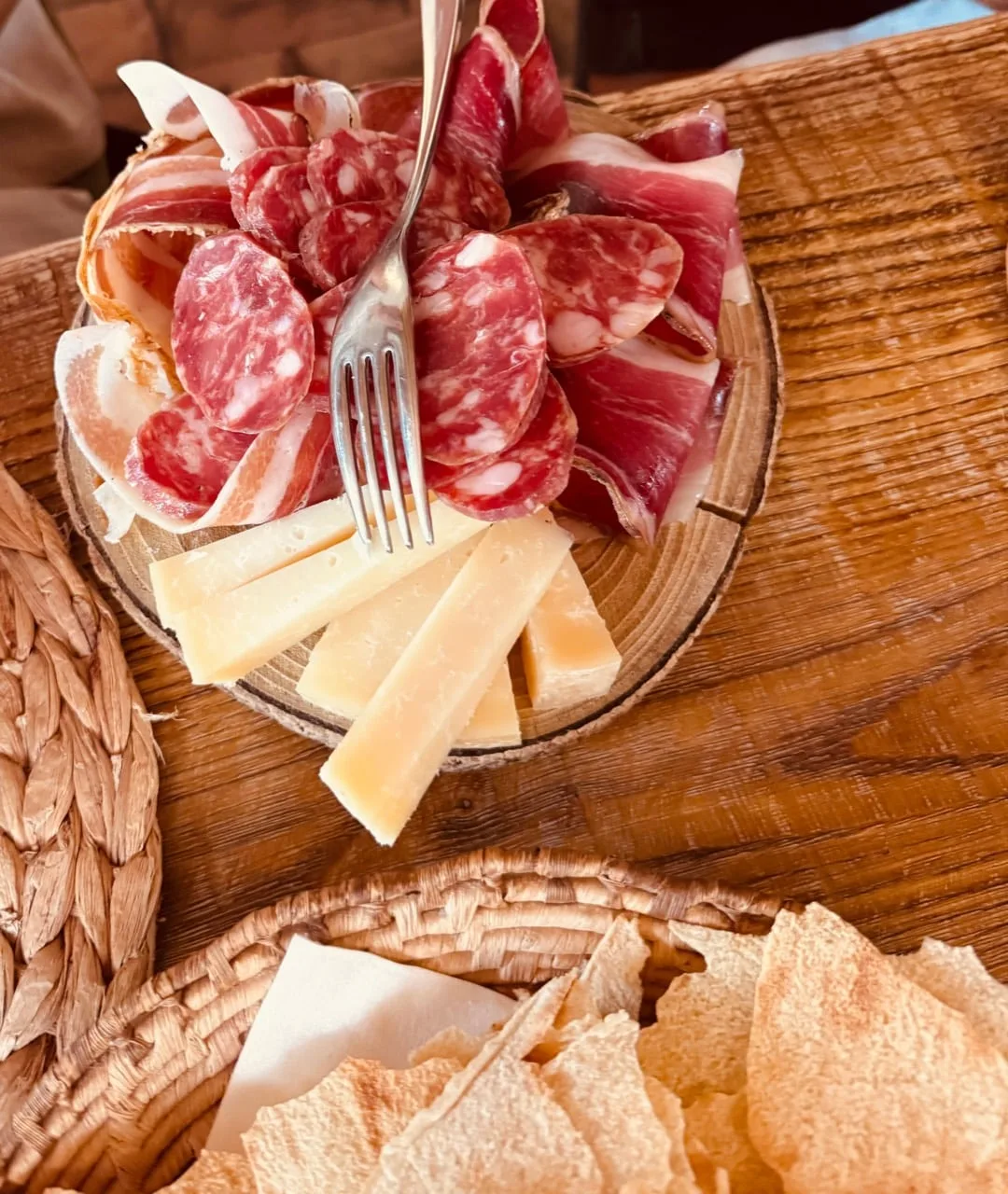 Local cured meats, aged cheese and crisp Sardinian bread on a wooden table